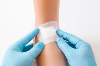 Image montrant un médecin posant un pansement sur l'avant-bras d'un patient