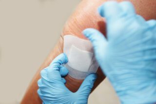 Infirmière posant un pansement sur le coude d'un patient