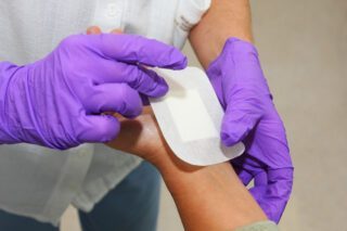 Image montrant un médecin posant un pensement sur la main d'un patient