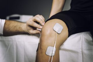Image montrant des électrodes TENS collés sur les genoux d'un patient